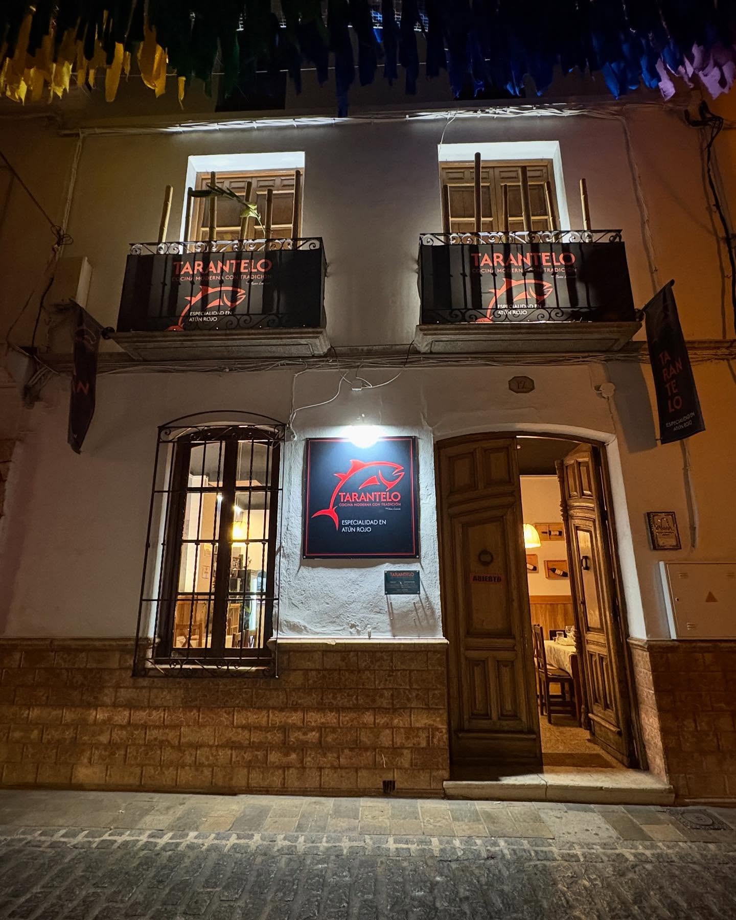 Fachada nocturna del restaurante TARANTELO con el rótulo de atún rojo sobre la pared